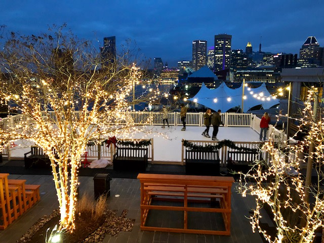 People ice skating at the Four Season Baltimore Hotel overlooking Baltimore's Inner Harbor.