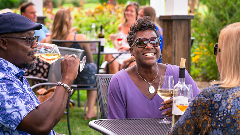 Three people sitting outside and enjoying a glass of wine together 