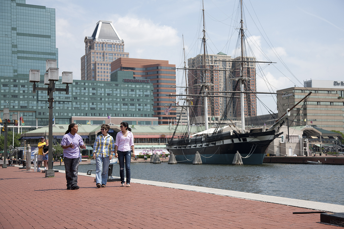 Three women walking along the Inner Harbor in Baltimore