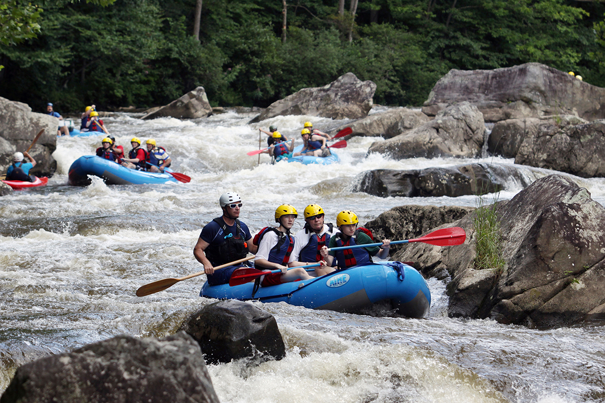 Several groups of Whitewater Rafters going down the rocky river.