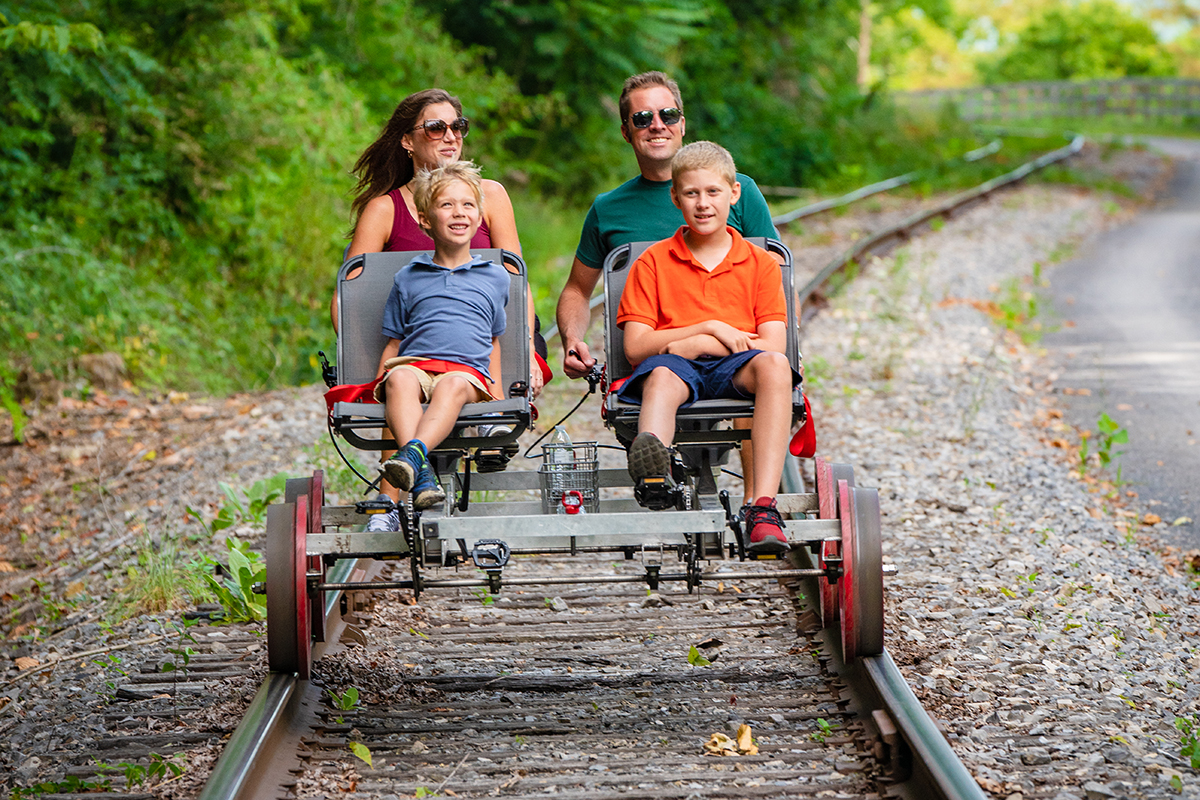 A family of four traveling down a railroad track on a pedal cart