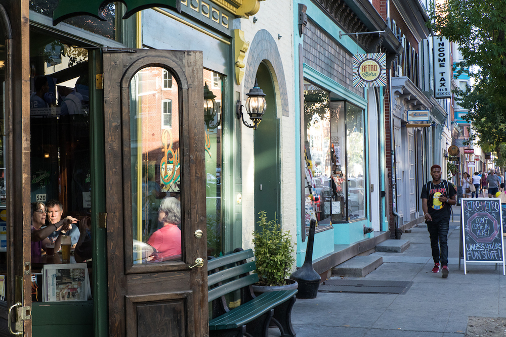 man walking past shops and restaurants in Frederick