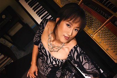 Vienna Teng leaning on piano Photo