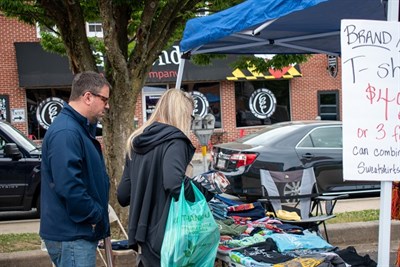 People searching through old clothing and miscellanea on a table outside Photo
