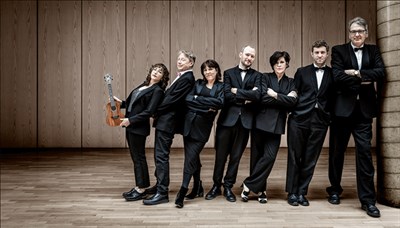 Ukulele Orchestra of Great Britain wearing tuxedos and leaning against each other. Photo