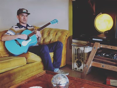 Wax sitting on a couch playing a guitar Photo