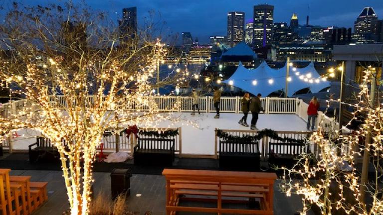 People ice skating at the Four Season Baltimore Hotel overlooking Baltimore's Inner Harbor.