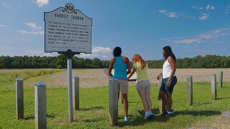 Three people observing the Harriet Tubman's Place of Birth Marker