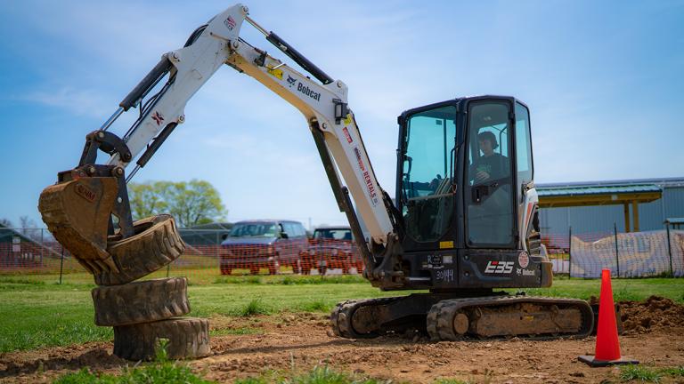 A person attempting to stack tires with a Bobcat Backhoe at Hagerstown's Heavy Metal Playground