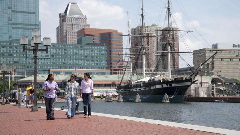 Three women walking along the Inner Harbor in Baltimore