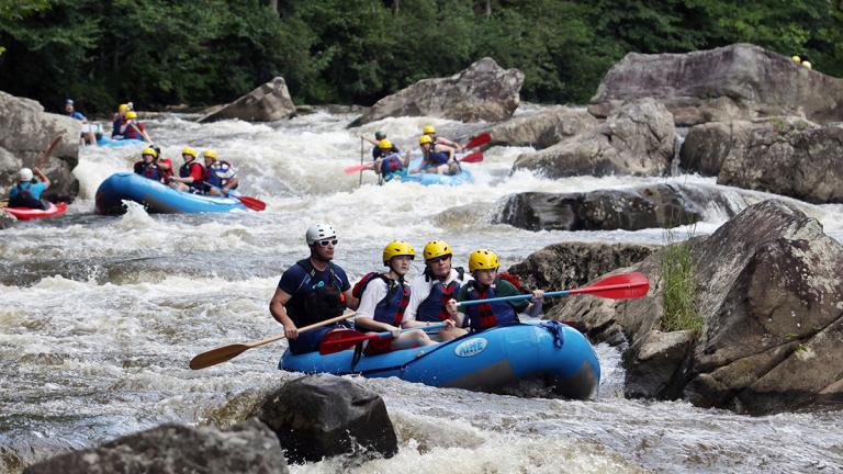 Several groups of Whitewater Rafters going down the rocky river.