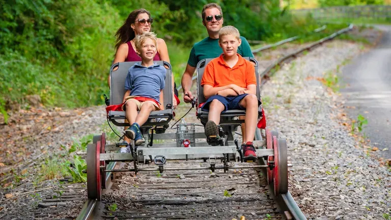 A family of four traveling down a railroad track on a pedal cart