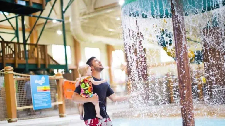 Father holds his daughter while in the Cub Paw Pool.