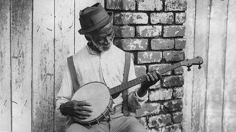 A man sitting and playing a banjo