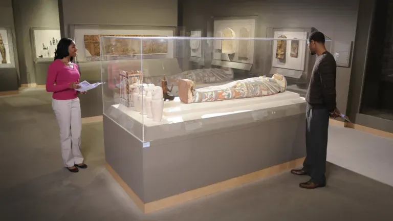 A man and woman viewing a mummy in a display case at the Walters Art Museum.