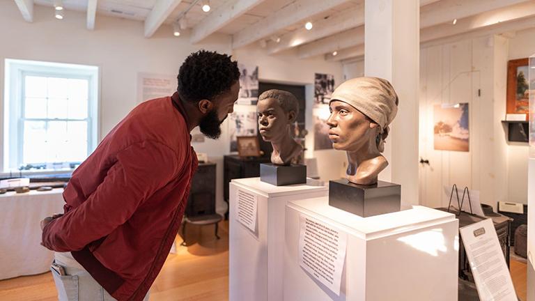 A man is viewing a bust of Harriet Tubman in a museum