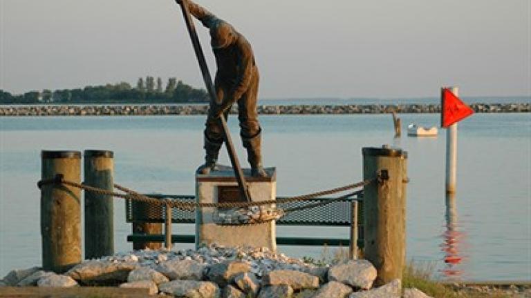 A statue of a waterman hand tonging for oysters