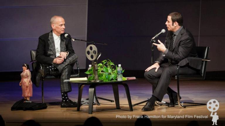 John Travolta on stage interviewing John Waters
