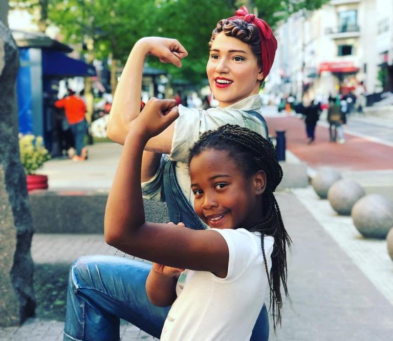 girl posing with Rosie the Riveter statue