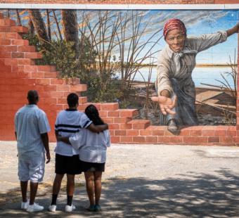 A family standing in front of and enjoying a mural of Harriet Tubman in Frederick, Maryland