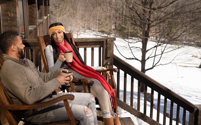 Couple sitting outdoors on a porch enjoying the snowy winter beauty.