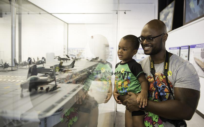Father and son viewing aircraft models in a showcase at Pax River