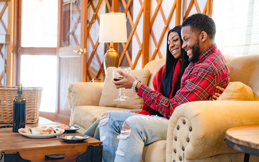 a couple relaxing with a bottle of wine and some snacks