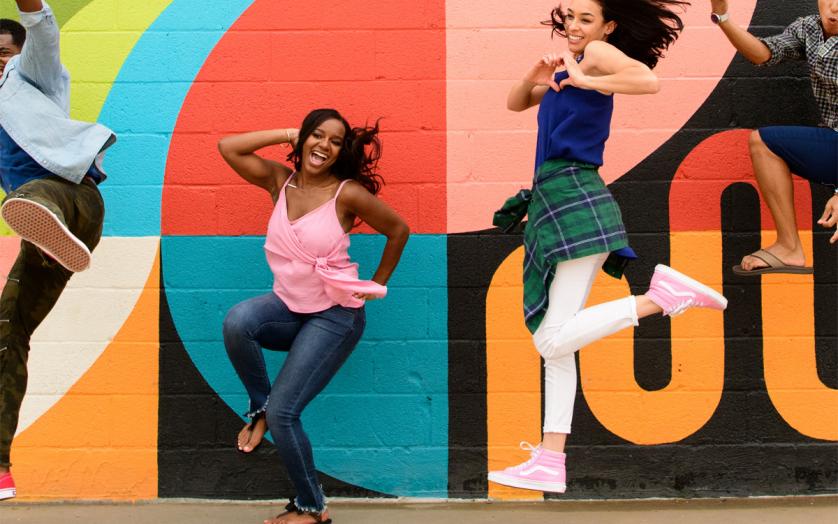 girls jumping in front of mural