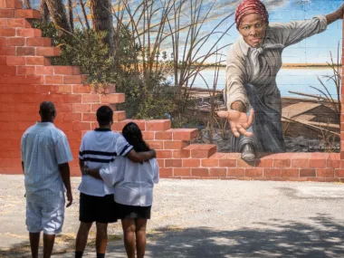 A family standing in front of and enjoying a mural of Harriet Tubman in Frederick, Maryland