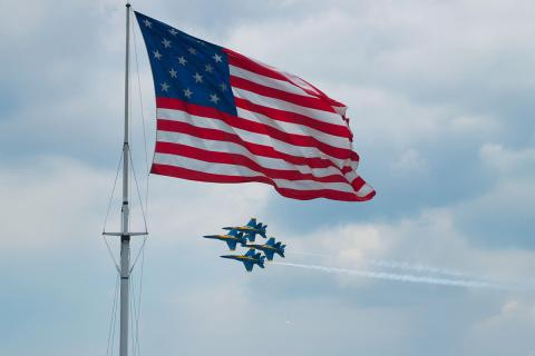The United State Navy Blue angels flying past the American flag flying over Fort McHenry.