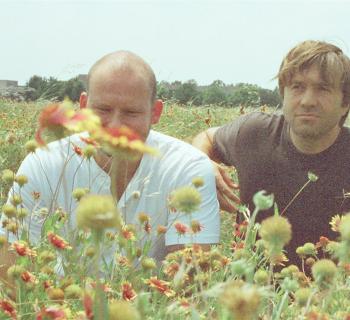 two men sitting a field of wildflowers Photo