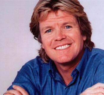 Peter Noone wearing a blue shirt and smiling Photo
