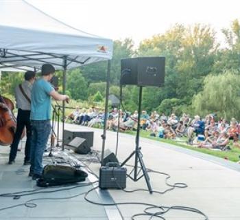 A musical group performs outdoors in front of a crowd. Photo