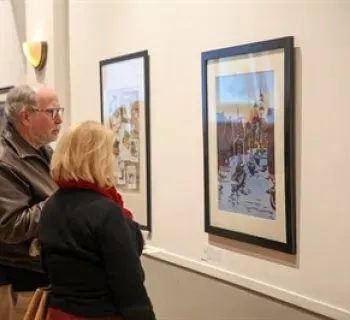 Two people observing the winning artwork at the 2023 Holiday Art Competition. Photo