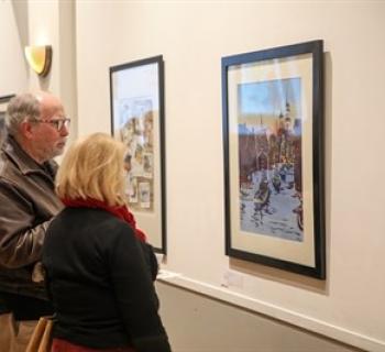 Two people observing the winning artwork at the 2023 Holiday Art Competition. Photo