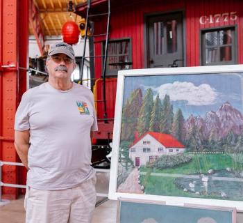 Man standing beside a screen painting. Photo