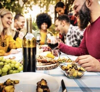Friends gathered around table enjoying wine and food Photo
