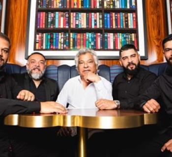 Gipsy Kings seated at a table, surrounded by books. Photo