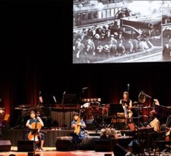 Silkroad Ensemble American Railroad orchestra performance in front of screen. Photo