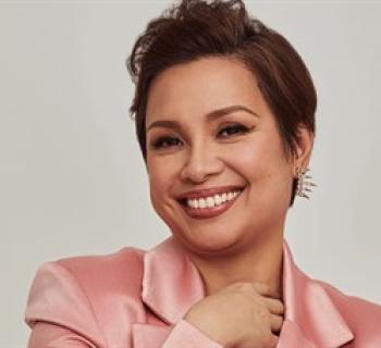 Lea Solanga smiling in a pink blouse. Photo