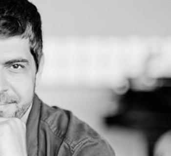 Andre Meharmi gazing into the camera with one hand on his chin. Photo