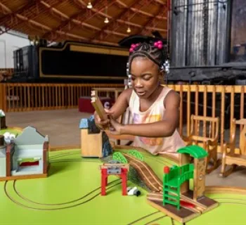 Young girl playing with a wooden train set. Photo