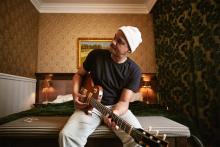 Son Little sitting on a bed playing guitar Photo