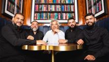 Gipsy Kings seated at a table, surrounded by books. Photo