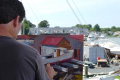 A Man Paints A Boat on Maryland's Eastern Shore Man works on a painting of a boat on the Eastern Shore