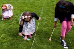 Three young ladies participating in an Easter Egg Roll race.