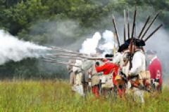 18th Century French, Indian and British reenactors 18th Century French, Indian and British reenactors lined up firing their rifles