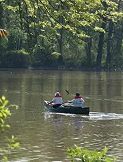 Two people in a kayak paddling a river.