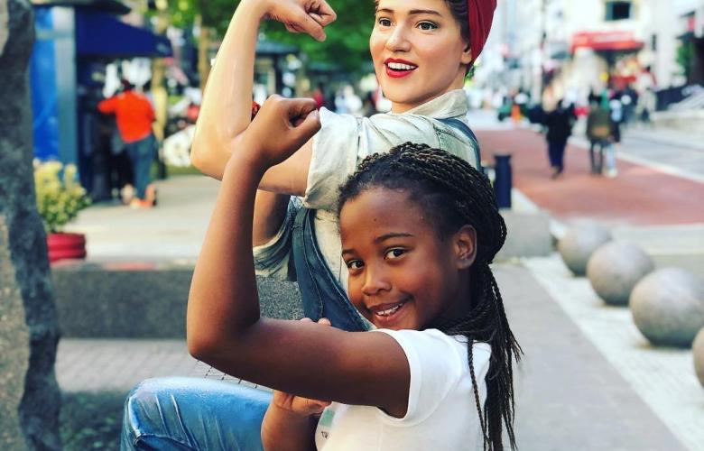 girl posing with Rosie the Riveter statue