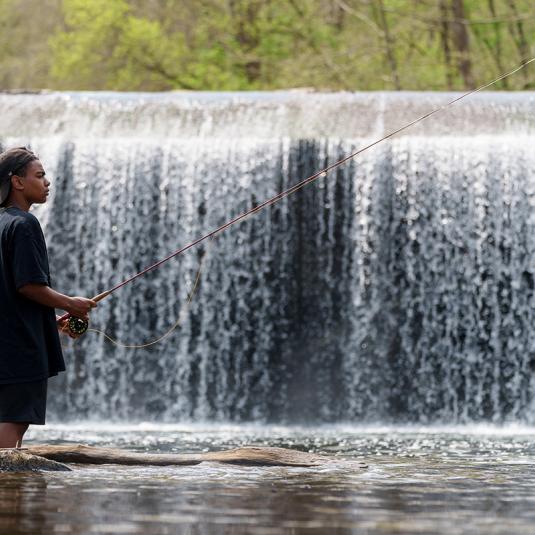 Boy fishing near a waterfall